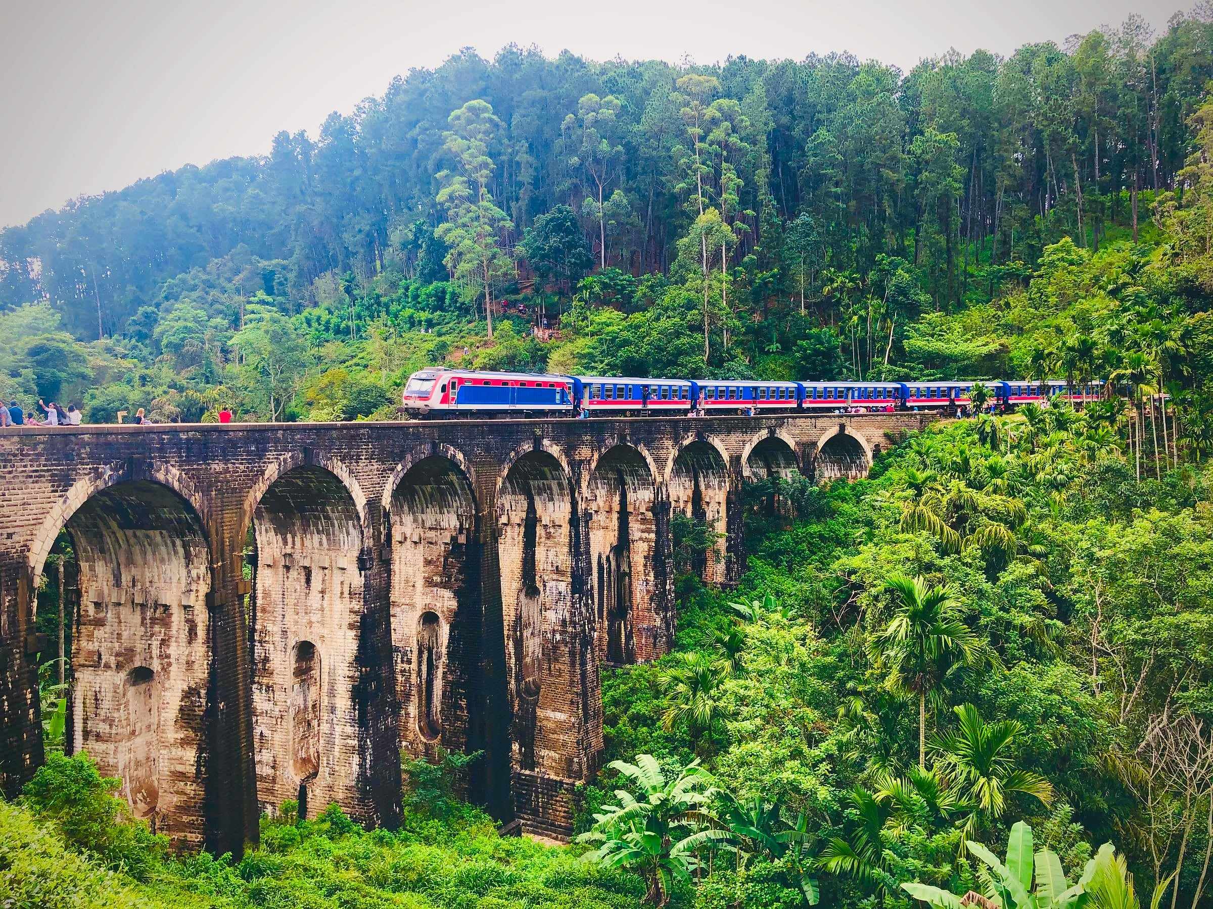 A blue train crossing the Nine Arch Bridge near Ella